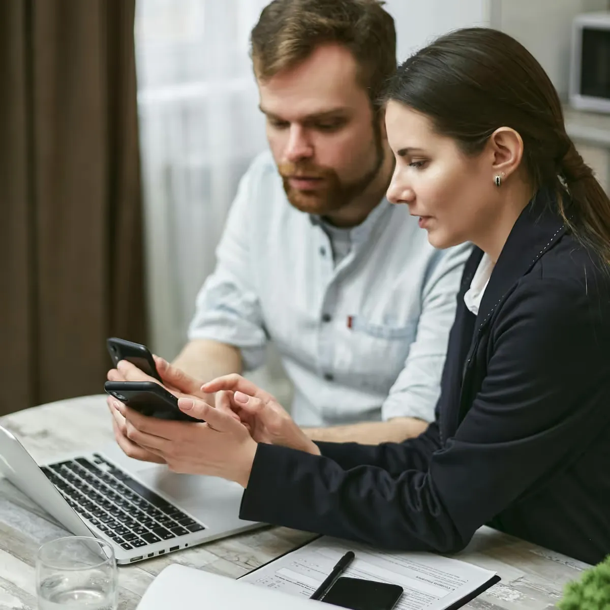 Zwei Versicherungsexperten besprechen Vertragsdetails am Laptop mit Unterlagen.